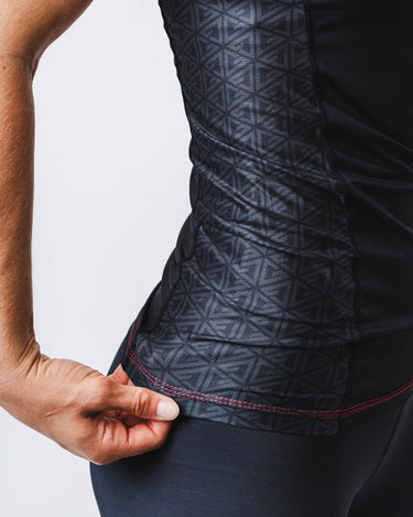 GB Essentials Women’s Ranked Rashguard in black, side panel close-up showing geometric pattern fabric and reinforced stitching at the hem.