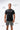 Flow Men's Tech Tee in black, full-length front view on a male model with the white Gracie Barra Stacked logo on the left chest