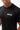 Flow Men's Tech Tee in black, chest close-up showing the white Gracie Barra Stacked logo on the left chest and the crew neckline