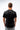 Flow Men's Tech Tee in black, back view on a male model showing the small white Brazilian Jiu-Jitsu graphic high on the upper back