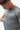 Flow Men's Tech Tee in dark grey, upper-body view of a model looking down and pinching the fabric, white Gracie Barra Stacked logo on the left chest