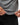 Flow Men's Tech Tee in dark grey, close-up of a model holding the curved hem out with both hands to show the fabric stretch