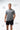 Flow Men's Tech Tee in dark grey, full-length front view on a male model standing with arms at his sides, white Gracie Barra Stacked logo on the left chest