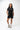 Flow Women's Tech Tee in black, full-length front view on a female model with hands in her pockets, white Gracie Barra Stacked logo on the left chest
