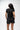 Flow Women's Tech Tee in black, full-length back view on a female model showing the small white Brazilian Jiu-Jitsu graphic on the upper back