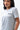 Flow Women's Tech Tee in light grey, upper-body three-quarter view on a female model with the dark Gracie Barra Stacked logo on the left chest
