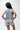Flow Women's Tech Tee in light grey, back view on a female model showing the small dark Brazilian Jiu-Jitsu graphic high on the upper back
