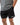 Frame Men's Short in black, three-quarter front view with a hand in the side pocket and a side hem vent, white Gracie Barra Stacked logo on the lower left leg