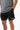 Frame Men's Short in black, three-quarter front view with a hand in the side pocket and a side hem vent, white Gracie Barra Stacked logo on the lower left leg