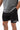 Frame Men's Short in black, lower-body front view with a hand in the side pocket, side hem vent, and the white Gracie Barra Stacked logo on the lower left leg