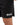 Frame Men's Short in black, close-up of a hand pulling the hem out to show the side hem vent, white Gracie Barra Stacked logo on the lower left leg