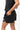 Frame Women's Short in black, side view with a hand in the side pocket and a side hem vent, white Gracie Barra Stacked logo on the lower left leg