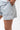 Frame Women's Short in light grey, lower-body close-up with a hand in the side pocket, side hem vent, white Gracie Barra Stacked logo on the lower left leg