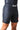Side view of a man in black GB Essentials velcroless training shorts showing the Gracie Barra logo, zip side pocket and side leg split