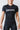 Woman wearing the black GB Essentials Womens Ranked Rashguard, front view with EQUIPE Gracie Barra chest print, red triangle logo and red stitching accents