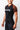 Angled side view of a woman wearing the GB Essentials Womens Ranked Rashguard, showing the brown raglan sleeve and textured side panels of the black compression top.