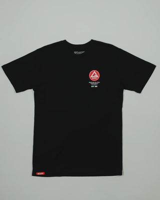 Black GB HQ 20th Anniversary Tee laid flat on a light gray background, featuring the red Barra Shield on the left chest and woven GB Wear label at the hem.