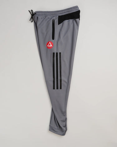 Gray GB Team Track Jogger by adidas folded with black stripes and red Gracie Barra logo visible, light gray background.