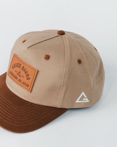 GB Trademark Cap shown from the side, highlighting white embroidered Legacy G logo and two-tone beige and brown construction.