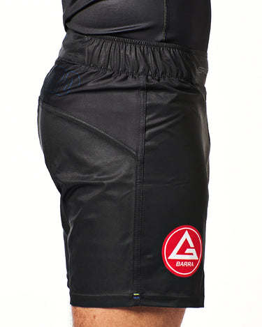 Side view of athlete wearing black Gracie Barra x Vanguard Evolution No Gi Shorts with red Barra Shield logo on right leg and tonal paneling details.