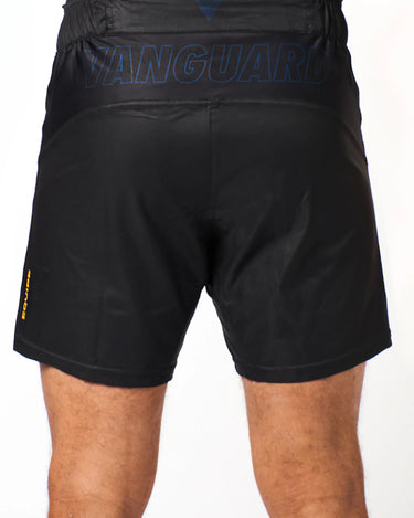 Athlete wearing black Gracie Barra x Vanguard Evolution No Gi Shorts with tonal blue “Vanguard” branding across waistband and yellow “Equipe” detail on left leg.