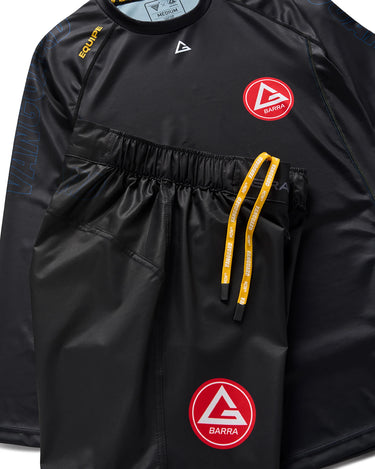 Black Gracie Barra x Vanguard Evolution No Gi set featuring long-sleeve rashguard with red Barra Shield chest logo and matching shorts with yellow drawstring and logo on left leg.