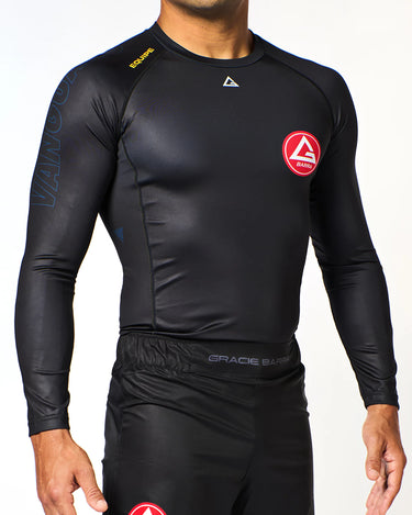 Athlete wearing black Gracie Barra x Vanguard Evolution rashguard with red Barra Shield chest logo, tonal Vanguard sleeve branding, and GB shorts.