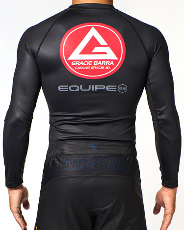 Athlete wearing black Gracie Barra x Vanguard Evolution rashguard back showing large red Barra Shield logo, “Equipe GB” lettering, and tonal Vanguard shorts branding.