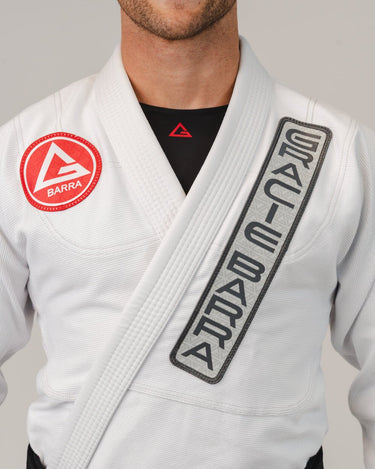 Close-up of the white GB1 Kimono showing the Red Shield chest patch, Gracie Barra lapel patch, and reinforced collar stitching for a strong, performance-driven fit.