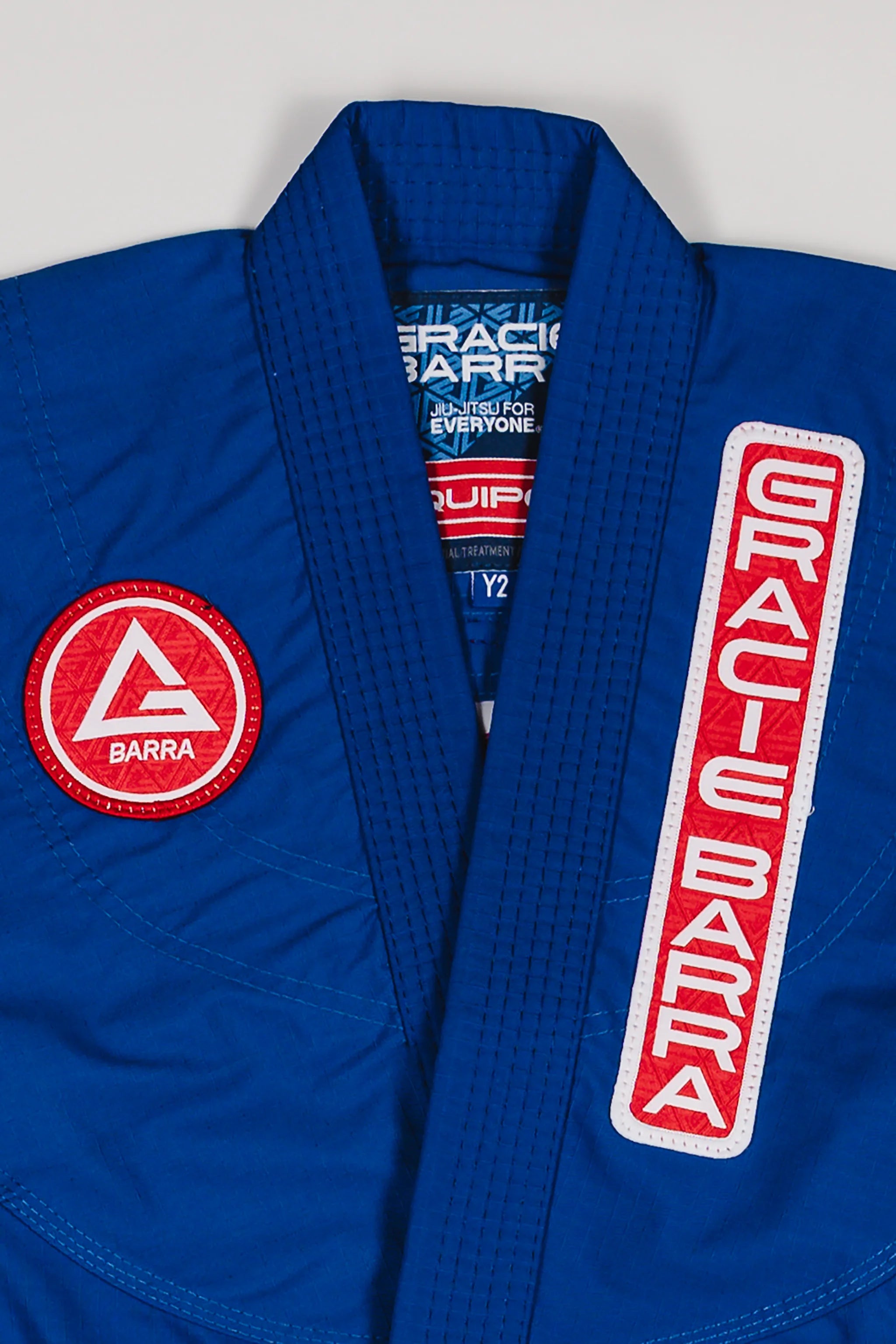 Close-up of Red Shield patch and Gracie Barra chest patch on the blue kids’ kimono.