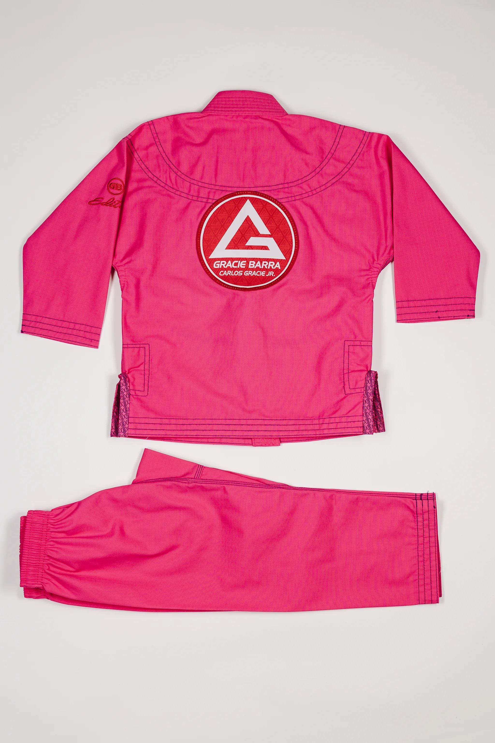 Back view of the pink GBK Lite Ripstop kids’ kimono set with a large Red Shield patch centered on the jacket. Shows the full jacket and pants to help parents see the fit and bright color young girls love.