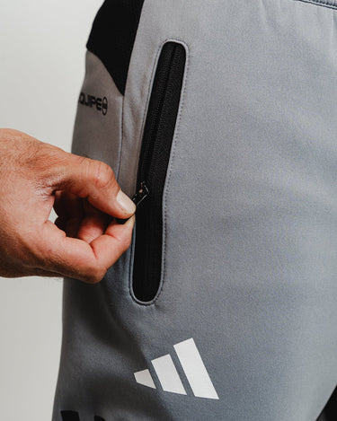 Close-up of zippered pocket with rubberized tab on gray GB Team Track Jogger by adidas.