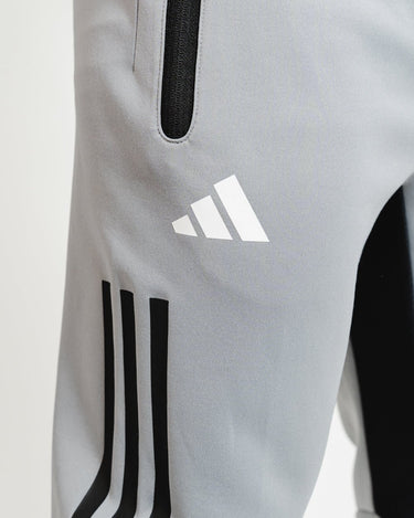 Close-up of adidas logo and black stripes on gray GB Team Track Jogger by adidas.