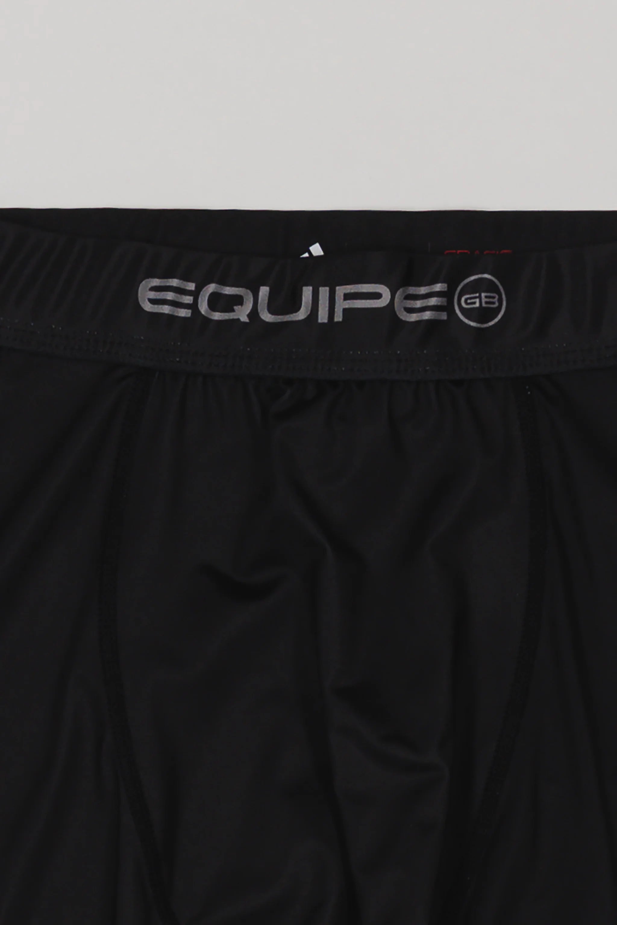 Close-up of the waistband on the black III Stripes Compression Pants by adidas, featuring silver EQUIPE GB branding.