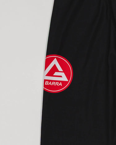 Close-up of the GB x adidas III Stripes Compression Pants showing the Red Shield logo printed on black performance fabric.