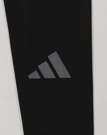 Close-up of the adidas Performance logo printed on the lower leg of the GB x adidas III Stripes Compression Pants in black.