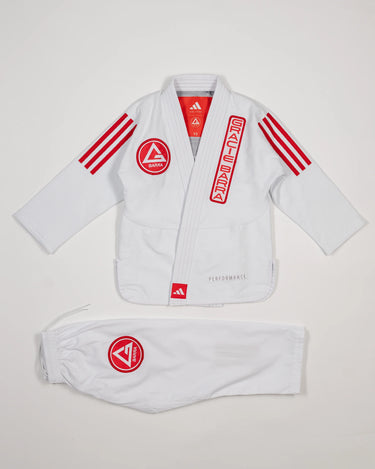White GB x adidas III Stripes Youth Kimono laid flat on white background, featuring bold red 3-Stripes on shoulders and red Gracie Barra patches on jacket and pants.