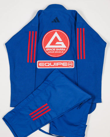 Back view of blue GB x adidas III Stripes Women’s Kimono with pants folded across jacket, featuring large Red Shield patch, red EQUIPE GB patch, and bold red 3-Stripes on shoulders and pant leg.