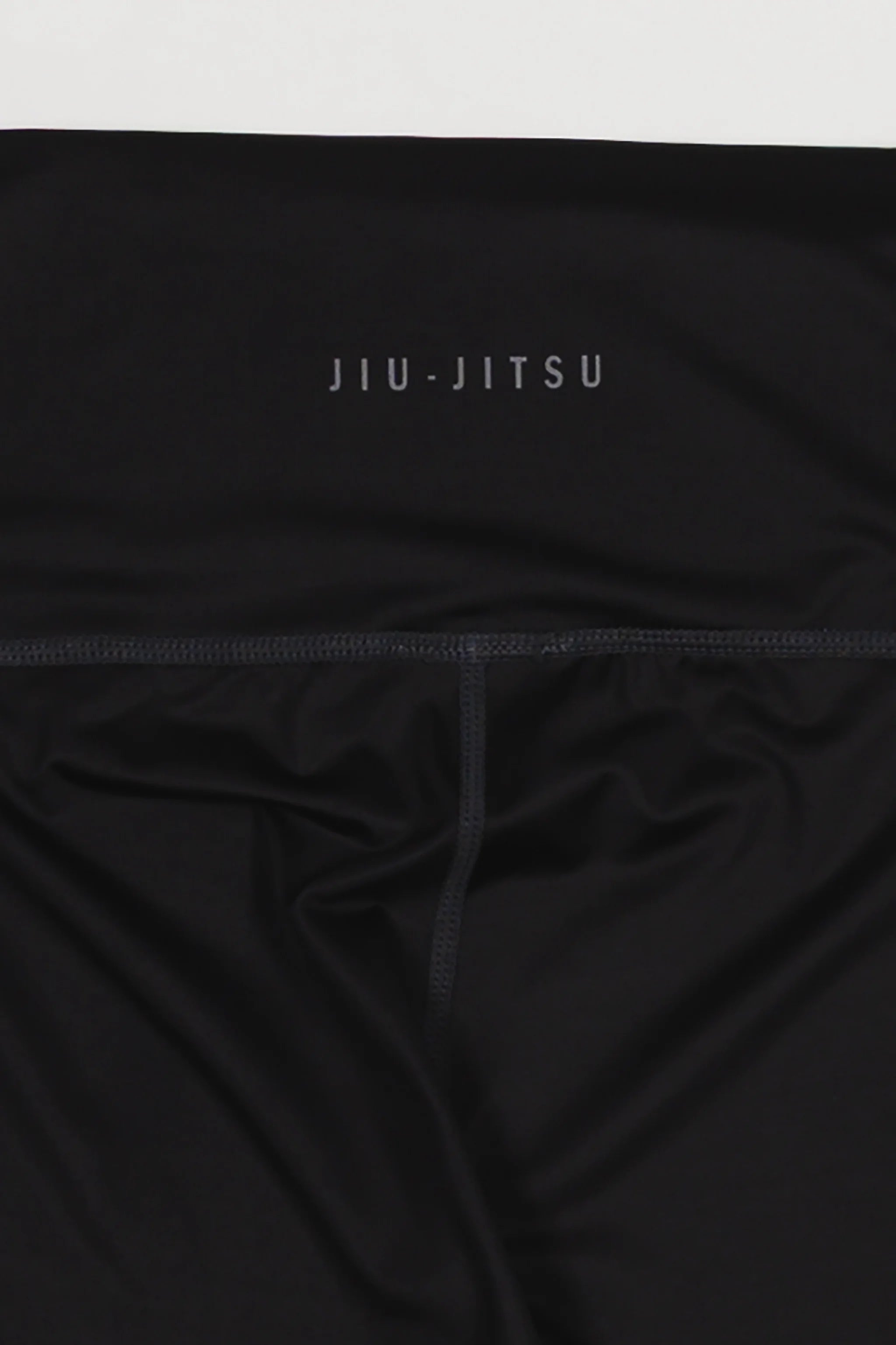 Close-up of the waistband on the GB x adidas III Stripes Women’s Compression Tights showing the “Jiu-Jitsu” text detail on black fabric.