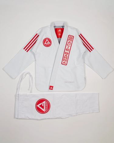 White GB x adidas III Stripes Women’s Kimono laid flat on white background, featuring bold red 3-Stripes on shoulders, red Barra Shield on chest, and Gracie Barra lapel patch with adidas Performance embroidery.