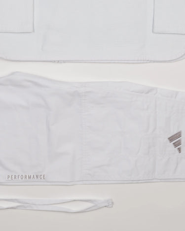 Detail view of white GB x adidas III Stripes Women’s Kimono jacket and pants on white background, showing embroidered adidas logo and tonal Performance text on pant leg.