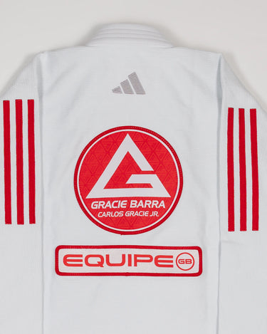 Close-up of white GB x adidas III Stripes Women’s Kimono back, showing embroidered Red Shield patch with Gracie Barra lettering, EQUIPE patch below, adidas logo at collar, and GB Red 3-Stripes on sleeves.