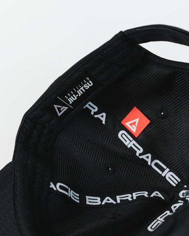 Inside view of black Gracie Barra Legacy G Performance Cap showing dual Legacy G logo details, “Gracie Barra Jiu-Jitsu” taping, and woven red Legacy G label.