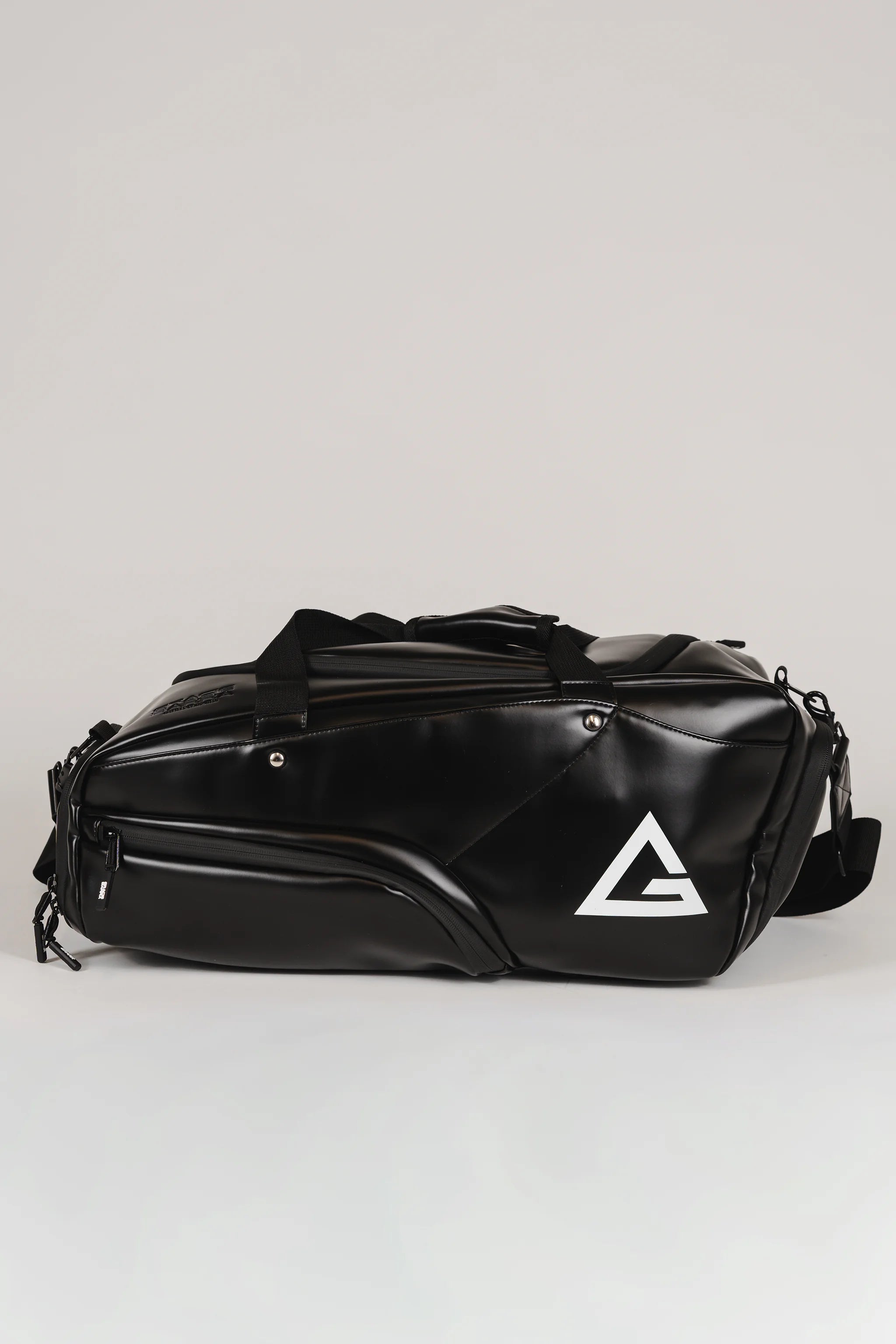 Black Legacy Travel Duffel shown from the side on a light gray background, featuring the white Legacy G logo and multiple zippered compartments.
