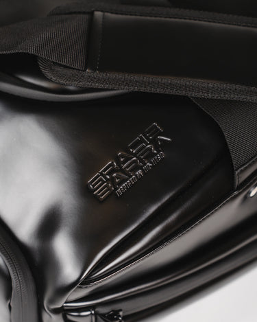 Close-up of the Legacy Travel Duffel’s debossed ‘Gracie Barra’ stacked wordmark on the smooth black exterior, shown with strap detailing and zipper hardware.