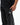 Legacy Windrunner pants in black, close-up on model showing the silver Legacy G logo, white side piping, and Gracie Barra text near the hem.