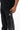 Legacy Windrunner pants in black, close-up on model showing the silver Legacy G logo, white side piping, and Gracie Barra text near the hem.
