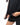 Legacy Womens Active Tee in black, close-up of model lifting the hem to show the lightweight performance fabric and flatlock seam.