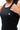 Legacy Womens Performance Racerback Tank in black, close-up of chest showing white Legacy G logo and scoop neckline on lightweight performance fabric.
