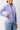 Lavender Gracie Barra Legacy Womens Track Jacket shown from the side with the funnel neck collar up and a hand in the zipper pocket.